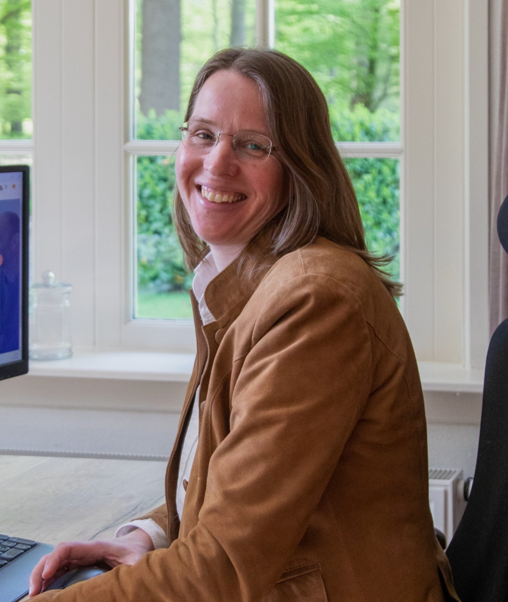 Astrid de Kroon aan haar bureau, portret in werkomgeving